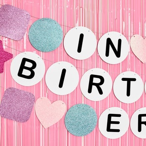 May include: A pink and white glitter birthday banner with the words "Happy Birthday" in black letters.