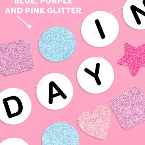 May include: A pink and blue glitter birthday banner with the word "Birthday" spelled out in white circles with black letters. The banner also includes a pink star, a pink heart, and two blue glitter circles.
