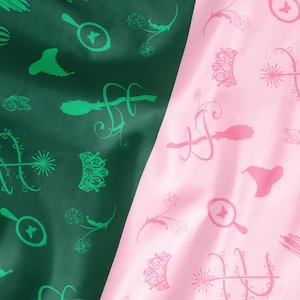 May include: A two-toned fabric with a dark green and pink color scheme. The fabric is patterned with various whimsical illustrations, including magnifying glasses, crowns, and floral elements. The design is repeated across the surface, creating a playful and decorative effect.