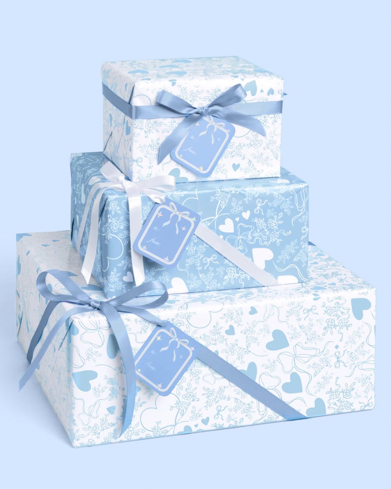 May include: Three gift boxes, stacked, wrapped in patterned paper with blue and white designs. Each box is tied with a ribbon and has a matching gift tag. The wrapping paper features hearts, bows, and floral patterns.
