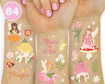 May include: A sheet of 84 temporary tattoos featuring fairies, mushrooms, flowers, and houses. The tattoos have a whimsical and magical theme. The text "Make a Wish" and "Magic" are included on the sheet.