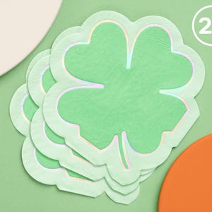 May include: A stack of 25 green shamrock-shaped paper napkins with a holographic finish.
