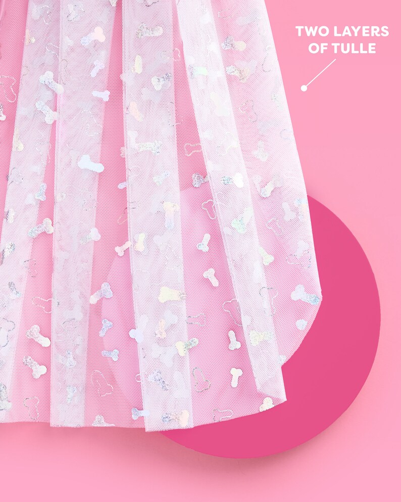 Peut inclure: Tissu de tulle blanc avec un motif d'os brillant. Le tulle est superpos&eacute; et a un fond rose.
