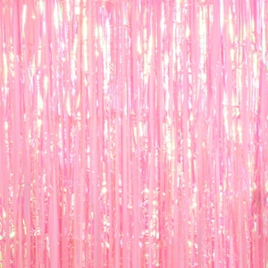 May include: A pink iridescent foil fringe curtain. The curtain is made of thin strips of foil that hang down in a vertical pattern. The foil is shiny and reflects light, creating a shimmering effect.