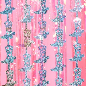 May include: A pink background with a repeating pattern of silver glitter cowboy boots. The boots are cut out and have a star design.