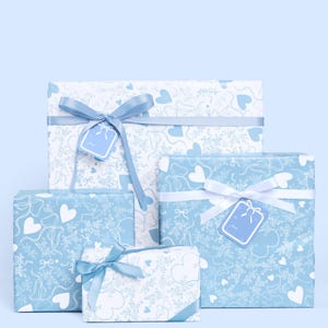May include: Four gift boxes of different sizes, wrapped in light blue paper with a white heart and bow pattern. Each box is tied with a satin ribbon and a matching gift tag. The background is a solid light blue.
