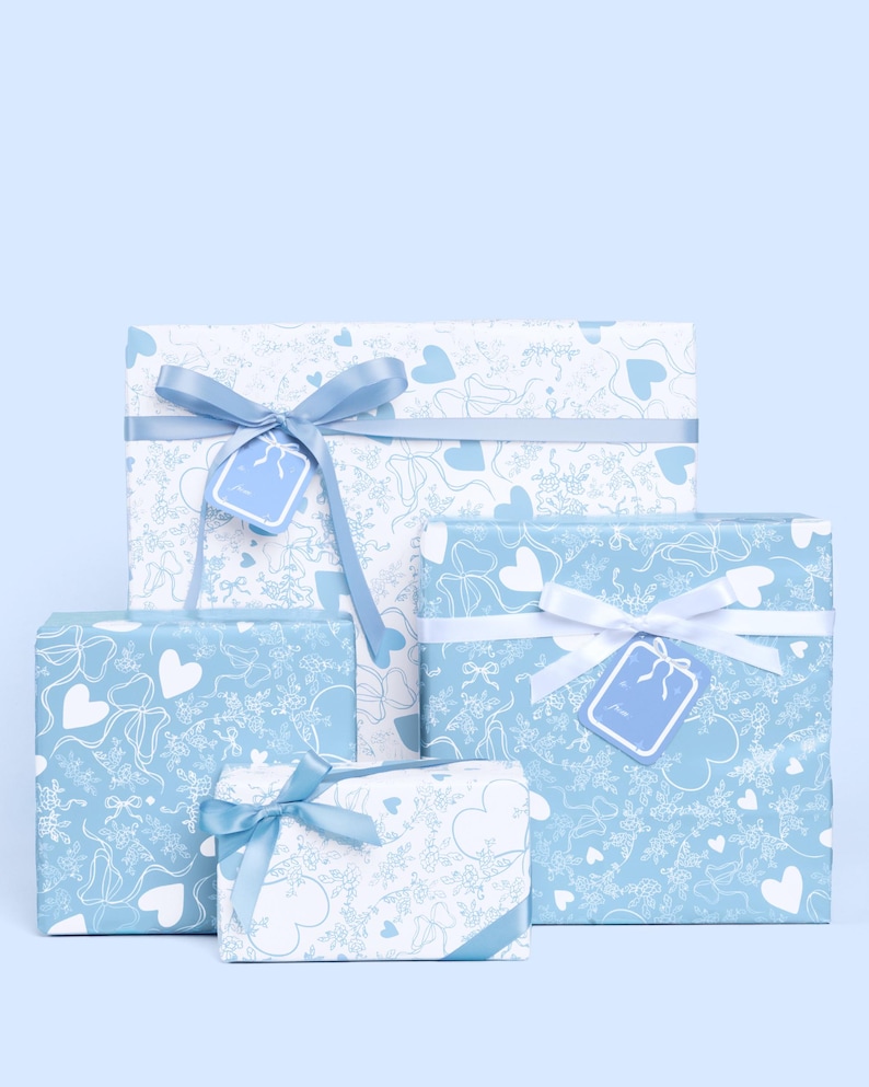 May include: Four gift boxes of different sizes, wrapped in light blue paper with a white heart and bow pattern. Each box is tied with a satin ribbon and a matching gift tag. The background is a solid light blue.