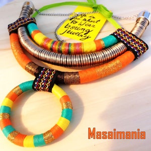 May include: A colorful multi-strand necklace with a silver chain and a circular pendant. The necklace is made of woven fabric and has a bright orange, yellow, turquoise, and black color scheme. The text "Life is too short to wear boring jewelry" is written on a yellow tag.