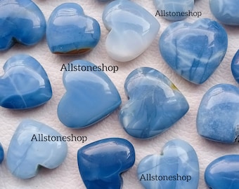 Puede incluir: Una colección de piedras de ópalo pulidas en forma de corazón azul y blanco. Las piedras son de varios tonos de azul y blanco, algunas tienen una apariencia más opaca que otras. Las piedras son todas en forma de corazón y tienen un acabado liso y pulido.