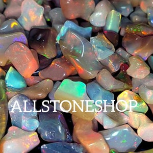 May include: A collection of iridescent opal chips in various shapes and sizes. The chips are a mix of light and dark colors, including blue, green, pink, and orange. The chips are perfect for jewelry making, crafts, and home decor.