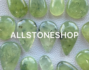 May include: A collection of green aventurine gemstone cabochons with black inclusions. The cabochons are teardrop shaped and have a smooth, polished finish.
