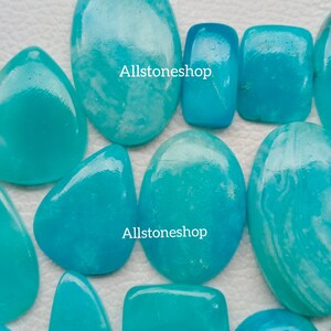 Puede incluir: Una colecci&oacute;n de diez piedras preciosas cabuj&oacute;n de color azul turquesa con vetas blancas. Las piedras son de diversas formas y tama&ntilde;os. El texto "Allstoneshop" aparece dos veces en la imagen.