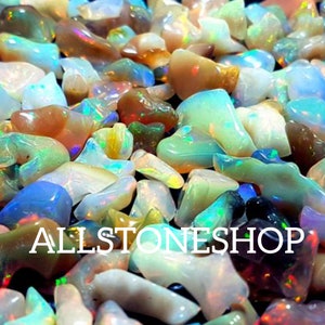 May include: A collection of iridescent opal chips in various shapes and sizes. The chips are a mix of white, blue, green, and brown colors. The chips are arranged in a random pattern. ALLSTONESHOP is printed in white text on the image.
