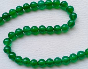 Op de afbeelding: Een streng groene agaat kralen. De kralen zijn rond en glad en zijn geregen op een doorzichtige draad.