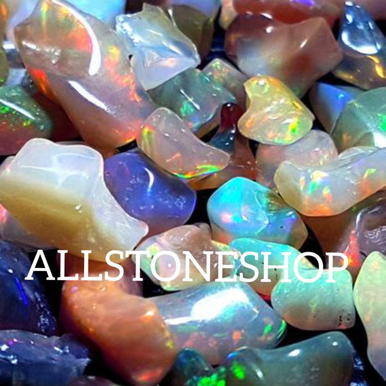 May include: A collection of colorful opal gemstones in various shapes and sizes. The opals have a rainbow iridescent sheen. The image includes the text "ALLSTONESHOP".