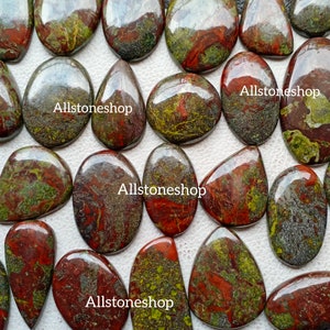 May include: A collection of 12 smooth, polished, green and red jasper cabochons. The stones have a variety of patterns and colours, including green, red, brown, and black. The stones are all approximately 2.5 cm in size.