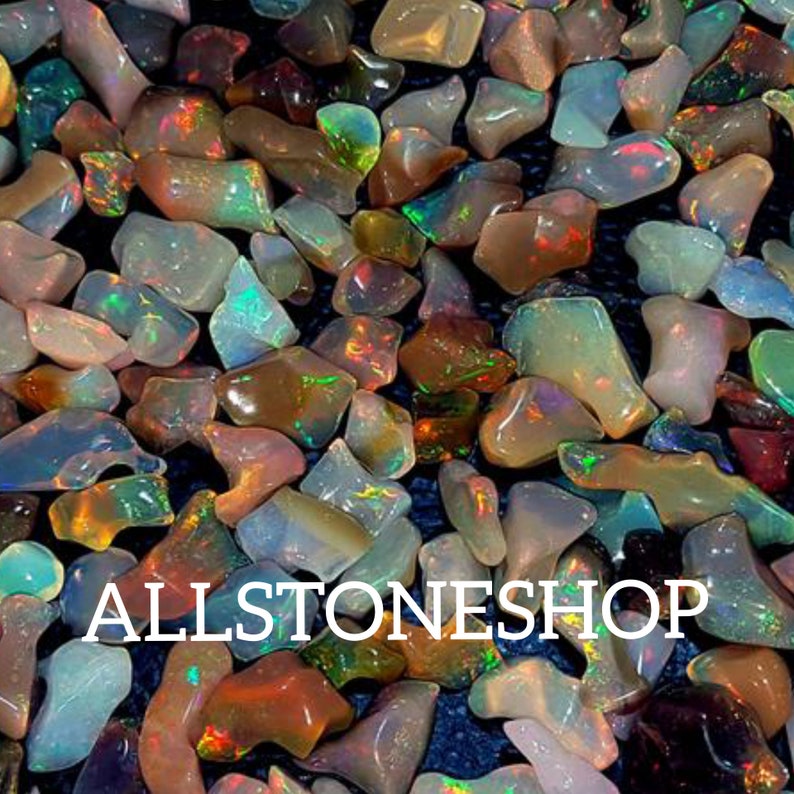 May include: A close-up of a collection of iridescent opal gemstones in various shapes and sizes. The opals are a mix of white, brown, and green colors with a rainbow sheen. The text "ALLSTONESHOP" is visible in the image.
