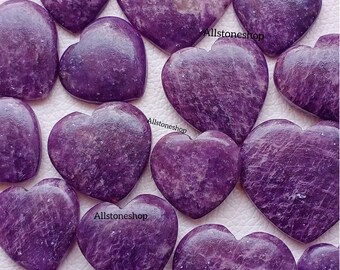 Puede incluir: Una colección de piedras de lepidolita en forma de corazón de color púrpura. Las piedras son lisas y pulidas, con una variedad de tonos de púrpura.