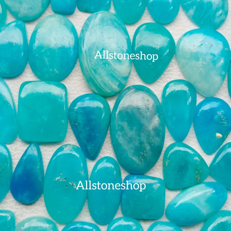 Puede incluir: Una colecci&oacute;n de piedras preciosas cabuj&oacute;n de color azul turquesa y blanco. Las piedras son de varias formas y tama&ntilde;os, incluyendo ovaladas, en forma de l&aacute;grima y cuadradas. Todas las piedras est&aacute;n pulidas y tienen un acabado liso y brillante. Allstoneshop est&aacute; escrito en la imagen.