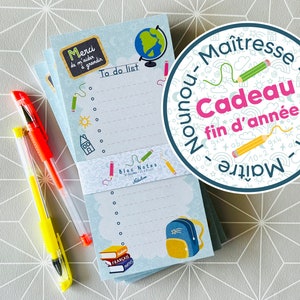 Peut inclure: Un bloc-notes bleu et blanc avec un design scolaire coloré. Le bloc-notes comporte une liste de choses à faire, un globe terrestre, un sac à dos et des livres. Le texte sur le bloc-notes dit "Merci de m'aider à grandir" et "Bloc Notes". Un stylo jaune et orange est à côté du bloc-notes. Un autocollant rond avec le texte "Nounou-Maîtresse-ATSEM-Maîtresse-Cadeau fin d'année" est en arrière-plan.
