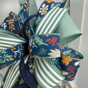 May include: A fall-themed bow featuring a blue and green floral print, green and white striped ribbon, and a solid navy blue ribbon.