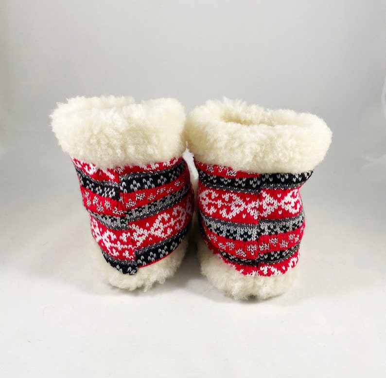 Puede incluir: Un par de zapatillas de estar por casa con estampado rojo, blanco y negro con forro de piel sint&eacute;tica blanca.