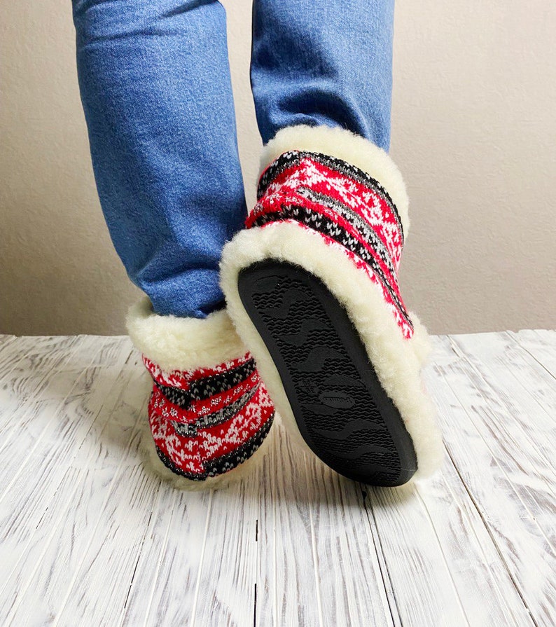 Puede incluir: Pantuflas de punto con estampado rojo y negro, forro de piel sint&eacute;tica blanca y suelas de goma negra.