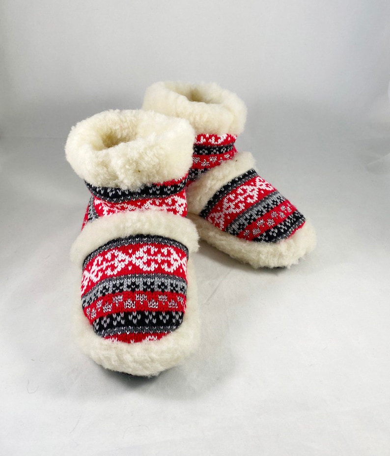 Puede incluir: Par de zapatillas de estar por casa de forro polar con estampado rojo, blanco y gris y pu&ntilde;o blanco.