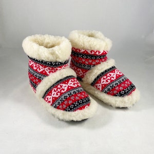 Puede incluir: Un par de zapatillas de estar por casa con estampado rojo, blanco y negro con forro de piel sint&eacute;tica blanca.