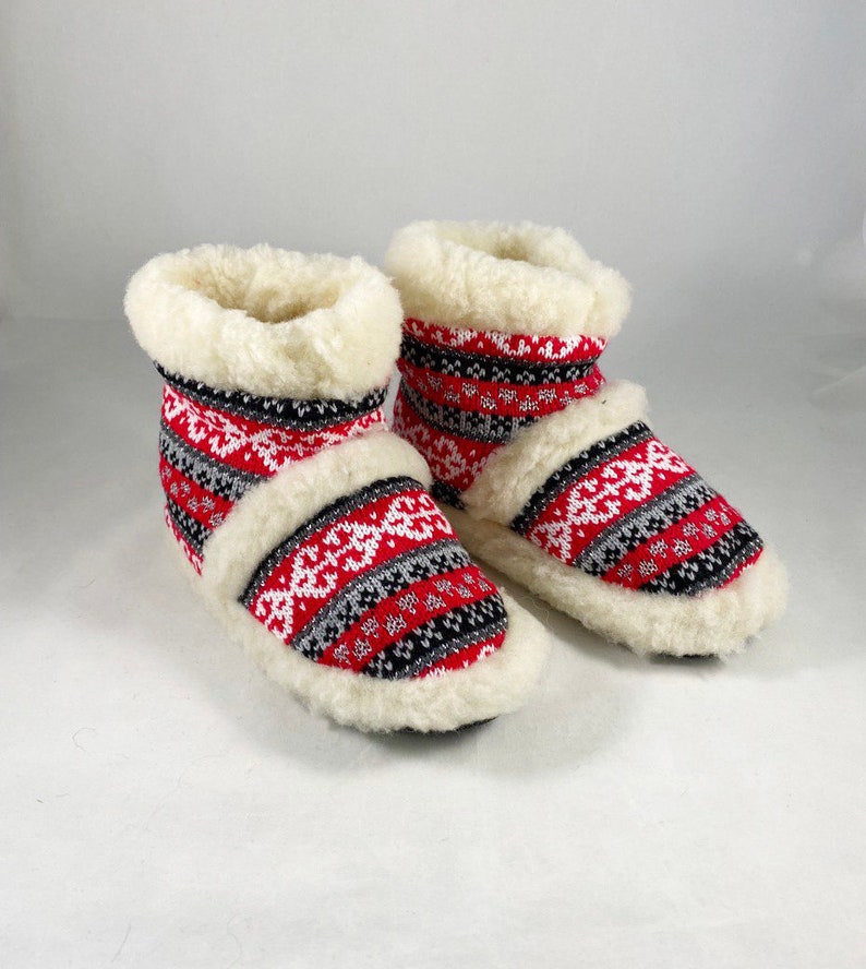 Puede incluir: Un par de zapatillas de estar por casa con estampado rojo, blanco y negro con forro de piel sint&eacute;tica blanca.
