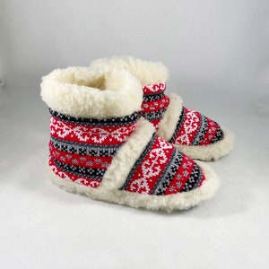 Puede incluir: Par de zapatillas de estar por casa de punto con estampado rojo, blanco y negro con forro de piel sint&eacute;tica blanca.