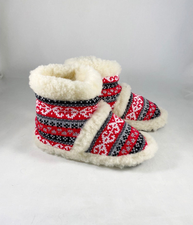 Puede incluir: Par de zapatillas de estar por casa de punto con estampado rojo, blanco y negro con forro de piel sint&eacute;tica blanca.