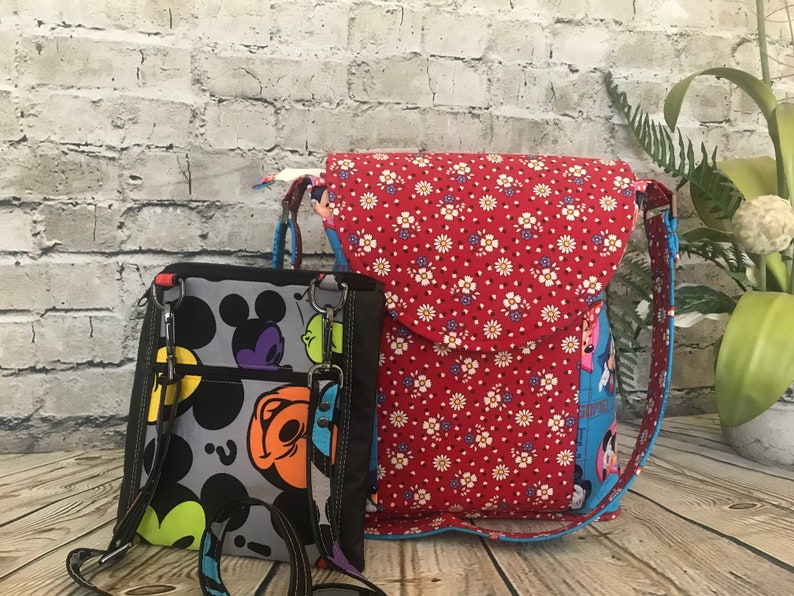 Puede incluir: Dos mochilas de tela con correas ajustables. La mochila m&aacute;s grande es roja con flores blancas y una correa azul. La mochila m&aacute;s peque&ntilde;a es negra con un patr&oacute;n de Mickey Mouse y correas de colores.