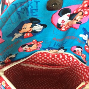 Puede incluir: Una bolsa de tela azul y roja con cierre de cremallera. La bolsa est&aacute; decorada con un patr&oacute;n repetido de personajes de Mickey Mouse y Minnie Mouse. El texto "Text Me" y "Awesome" est&aacute; impreso en la bolsa.
