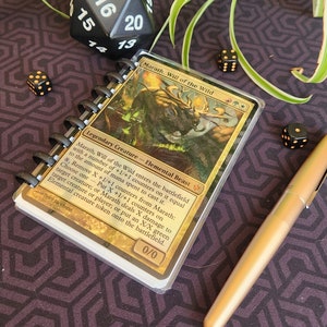 Puede incluir: Una carta de Magic: The Gathering con Marath, Voluntad de la Selva, una criatura de bestia elemental verde y dorada con una fuerza y resistencia de 0/0. El texto de la carta dice: "Marath, Voluntad de la Selva entra al campo de batalla con un número de contadores +1/+1 sobre ella igual a la cantidad de maná gastado para lanzarla. x, Eliminar X contadores +1/+1 de Marath: Elige uno - Pon X contadores +1/+1 sobre la criatura objetivo; o Marath inflige X daño a la criatura o jugador objetivo; o pon una ficha de criatura elemental verde X/X en el campo de batalla."