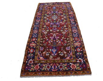 Könnte beinhalten: Ein langer, schmaler Teppich mit traditionellem persischem Design. Der Teppich hat einen dunkelroten Hintergrund mit komplizierten Blumenmustern in Blautönen, Grün, Rosa und Gelb. Der Rand ist in einem satten Goldton mit einem sich wiederholenden Blumenmotiv.