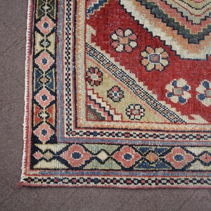 May include: Close-up of the bottom edge of a red, beige, blue, and black patterned rug. The rug has a geometric design with floral motifs.