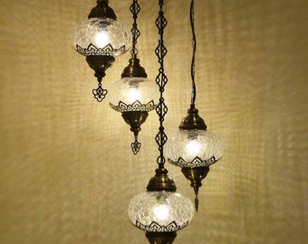 May include: A chandelier with four clear glass globes and a metal frame. The globes have a textured surface and are suspended from the frame by chains.