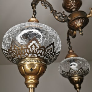 May include: A three-light chandelier with ornate brass fixtures and clear glass globes with a crackled finish.