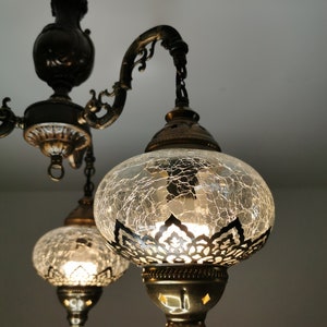 May include: A three-light chandelier with a black metal frame and clear glass globes. The globes have a crackled glass finish and a decorative metal trim.