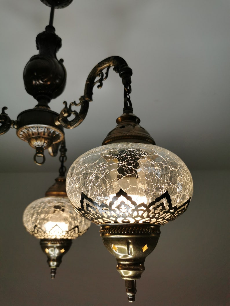 May include: A three-light chandelier with a black metal frame and clear glass globes. The globes have a crackled glass finish and a decorative metal trim.