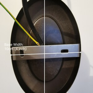 May include: A dark brown oval-shaped ceiling light fixture. The base width is 4 inches, and the base height is 6 inches. The fixture has a metal bracket and a black wire. The text "Base Width: 10cm (4 inch)" and "Base Height: 16cm (6 inch)" are visible.