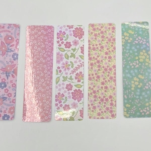 May include: Five rectangular bookmarks with floral patterns. The designs include pink, purple, and green flowers on various backgrounds. The bookmarks are arranged vertically, showcasing the different floral arrangements.
