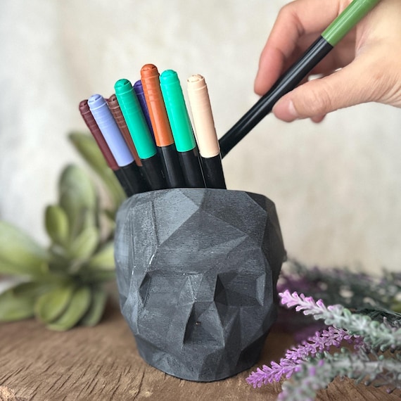A geometric skull cast in raw concrete doubles as a planter, candle holder, or pure desk sculpture — moody, architectural, and way cooler than any ceramic pot on the shelf.