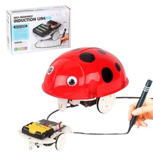 May include: A red ladybug-shaped toy robot with black spots and googly eyes follows a black line drawn on a white surface. The robot is connected to a smaller, white, battery-powered base with wheels. The toy is part of a self-assembly induction line set.