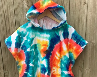 May include: A hooded poncho with a vibrant tie-dye pattern. The colors include blue, turquoise, orange, yellow, and white. The poncho is made of a soft, absorbent material, perfect for the beach or pool.