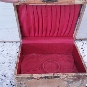 May include: An antique wooden box with a red velvet interior. The box has a hinged lid and a small ring holder inside.