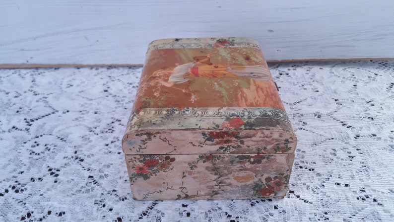 May include: A vintage wooden box with a floral design and a faded image of a woman on the lid. The box is painted in shades of pink, green, and brown.