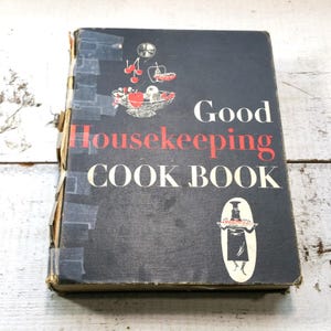 May include: Vintage Good Housekeeping Cookbook with a black cover and red and white text. The cover features illustrations of a bowl of fruit and a chef holding a platter of food.