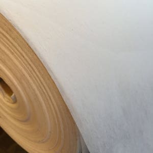 May include: A roll of white paper with a brown cardboard core. The paper is rolled up tightly and the core is visible at the edge of the roll.